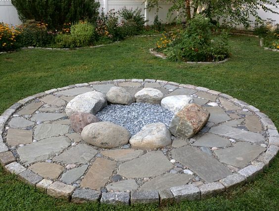 Round mosaic fire ring created with large grey beach pebbles and smaller black river rocks